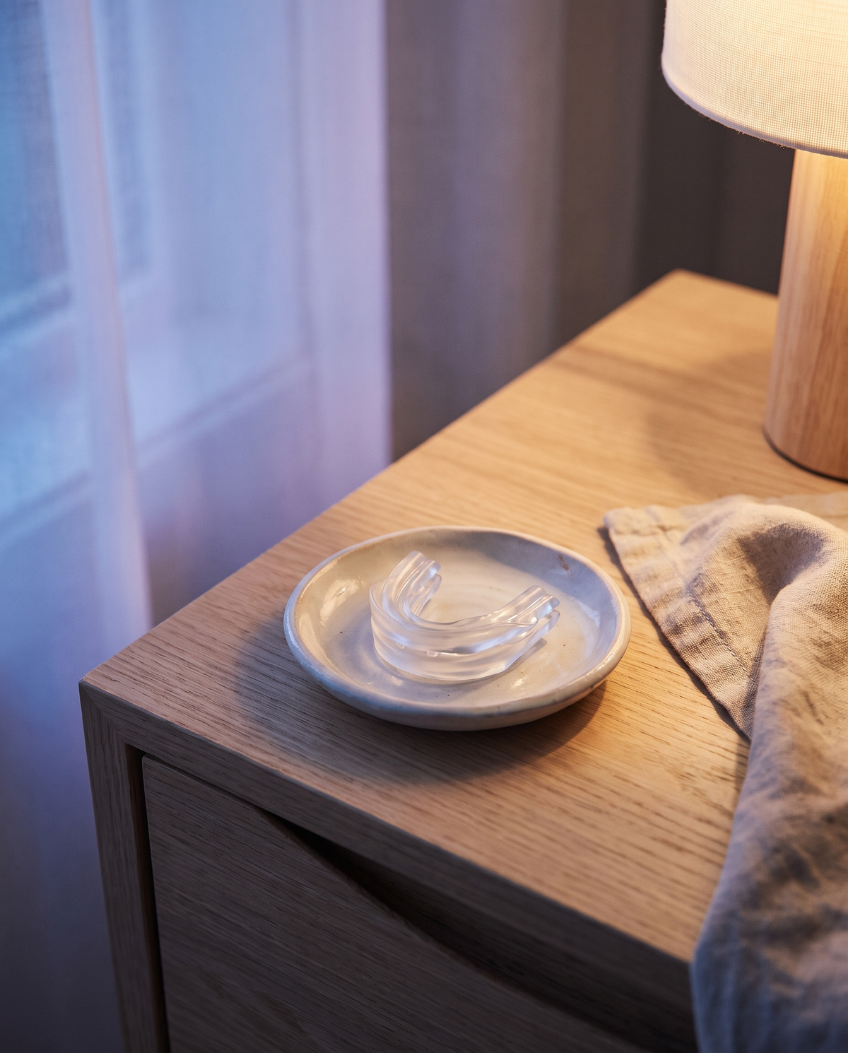 La gouttière posée dans une coupelle en céramique sur une table de nuit