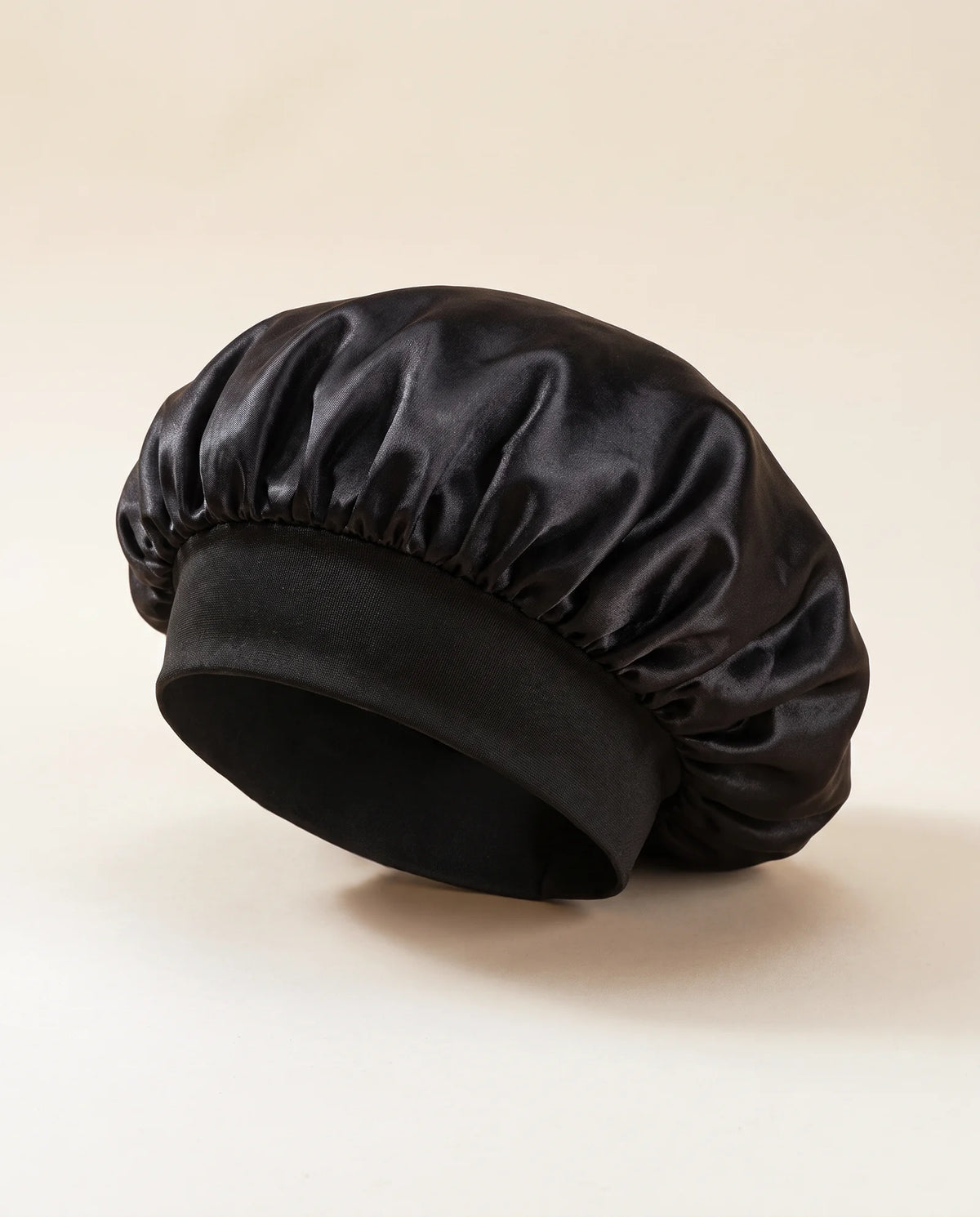 Bonnet en satin noir sur fond sable
