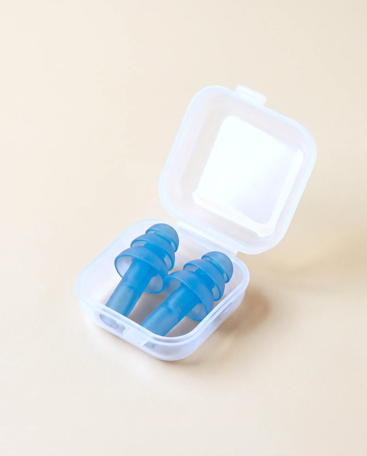 Bouchons d'oreille en silicone et leur boîte, sur fond sable