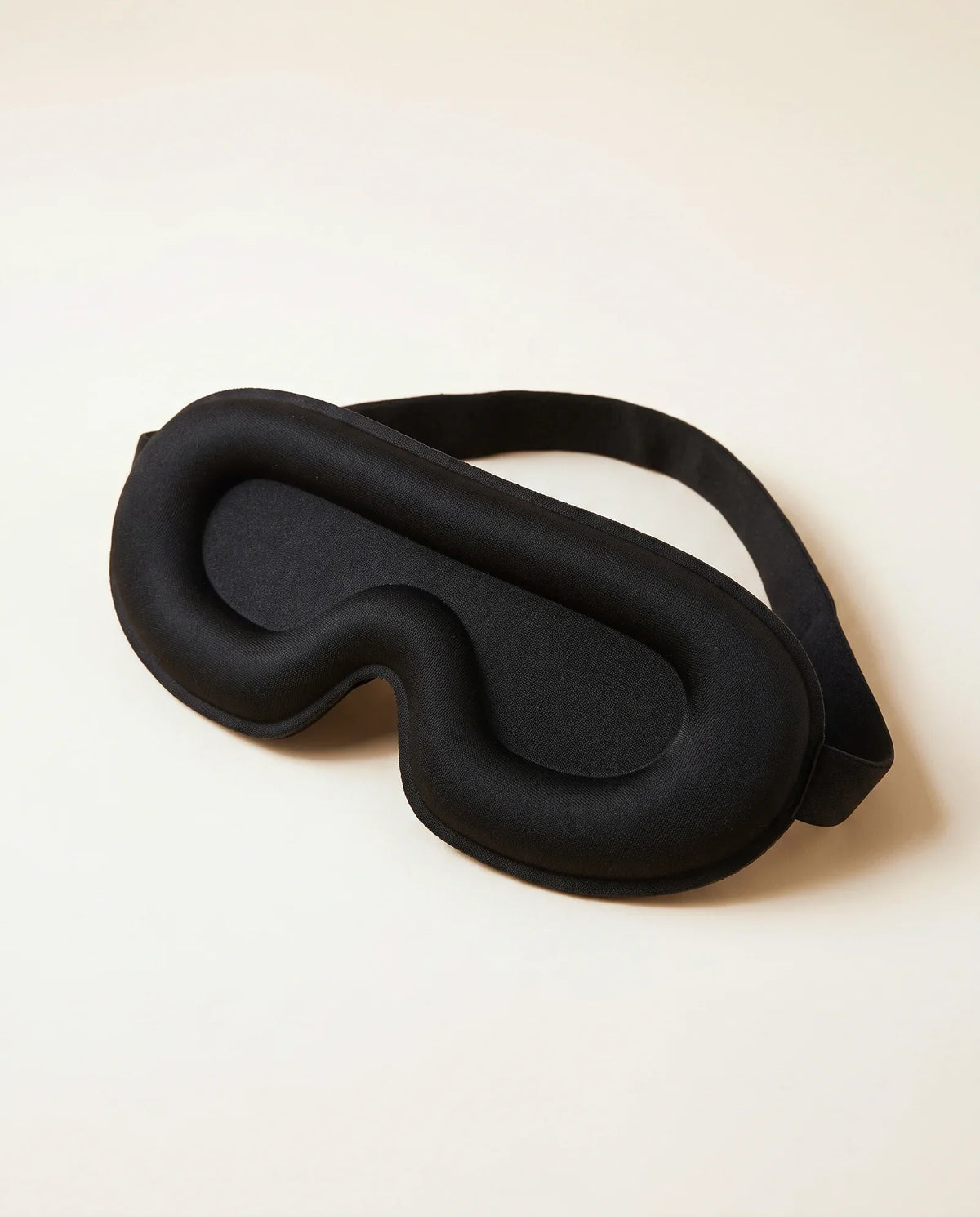 Masque 3D Bluetooth noir, vu de trois quarts sur fond sable
