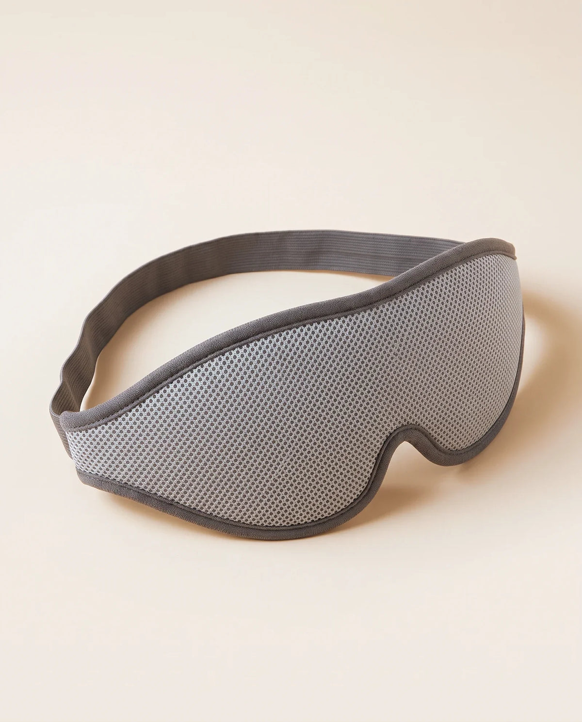 Masque 3D occultant gris, vu de trois quarts sur fond sable