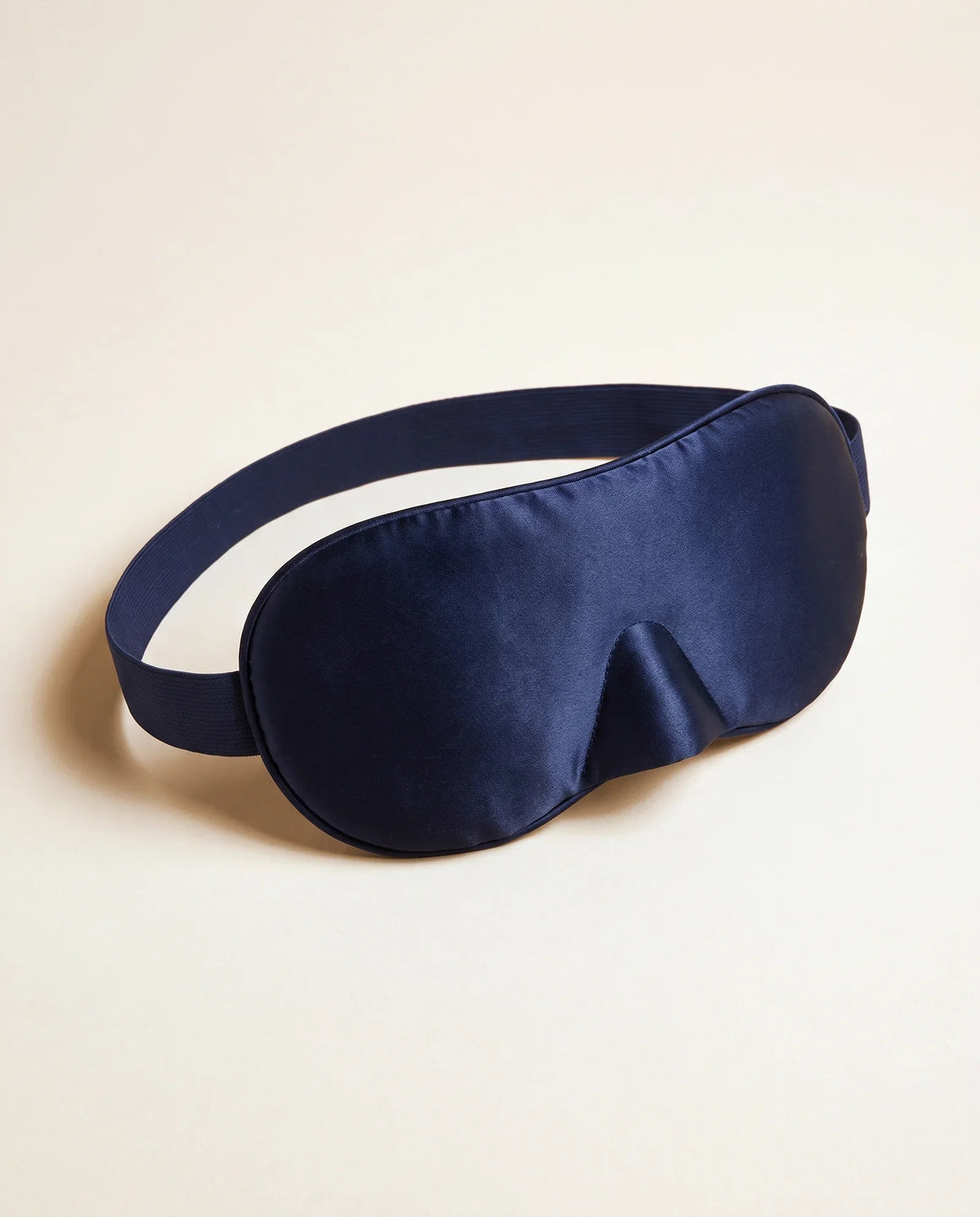 Masque en soie bleu nuit, vu de trois quarts sur fond sable
